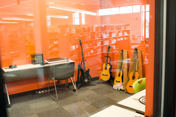 Book shelves are reflected in the music studio's windows.